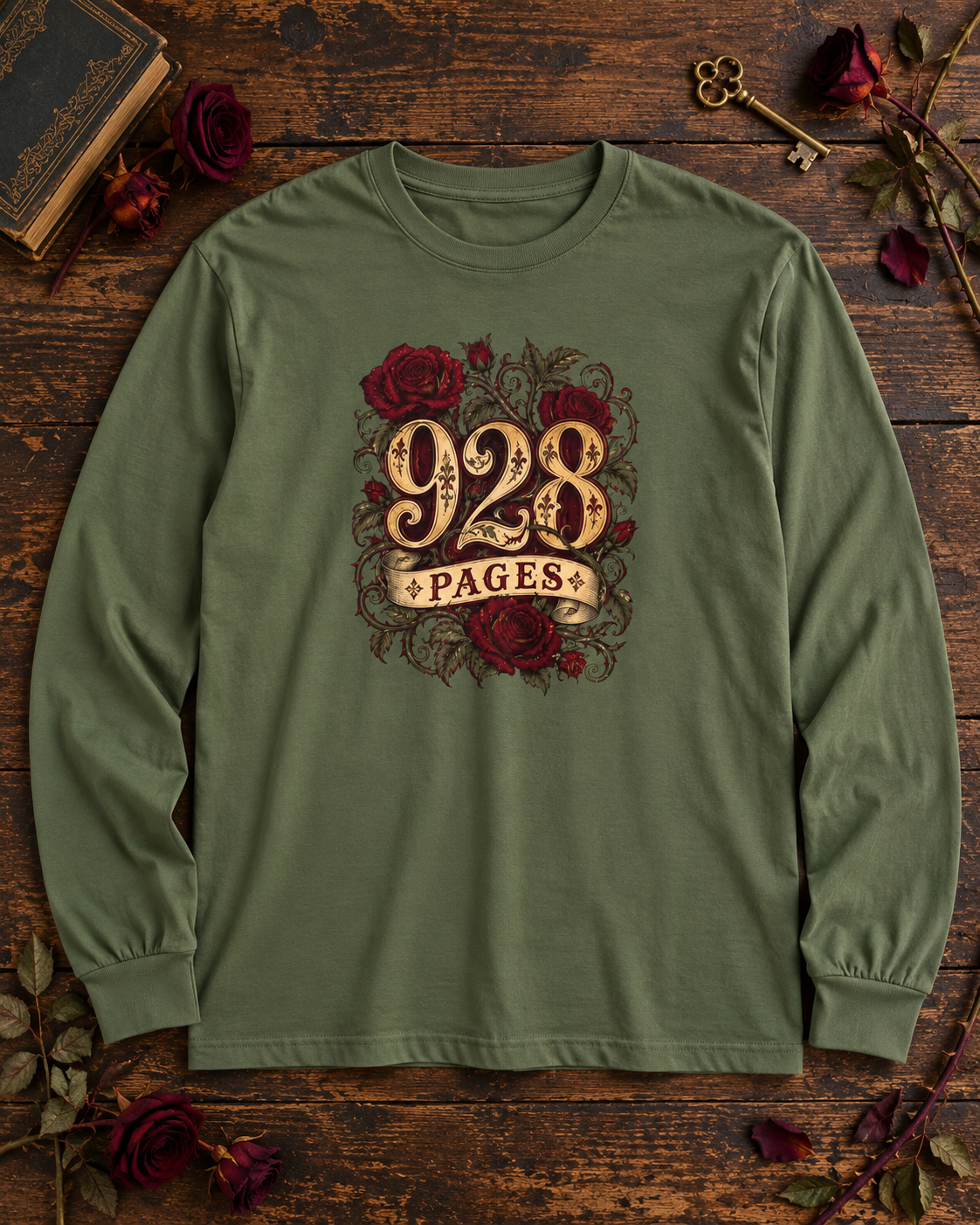 Hemp green long sleeve shirt with ornate gold 928 PAGES lettering wrapped in red roses and thorny vines, on a wood table with an antique book and dried roses
